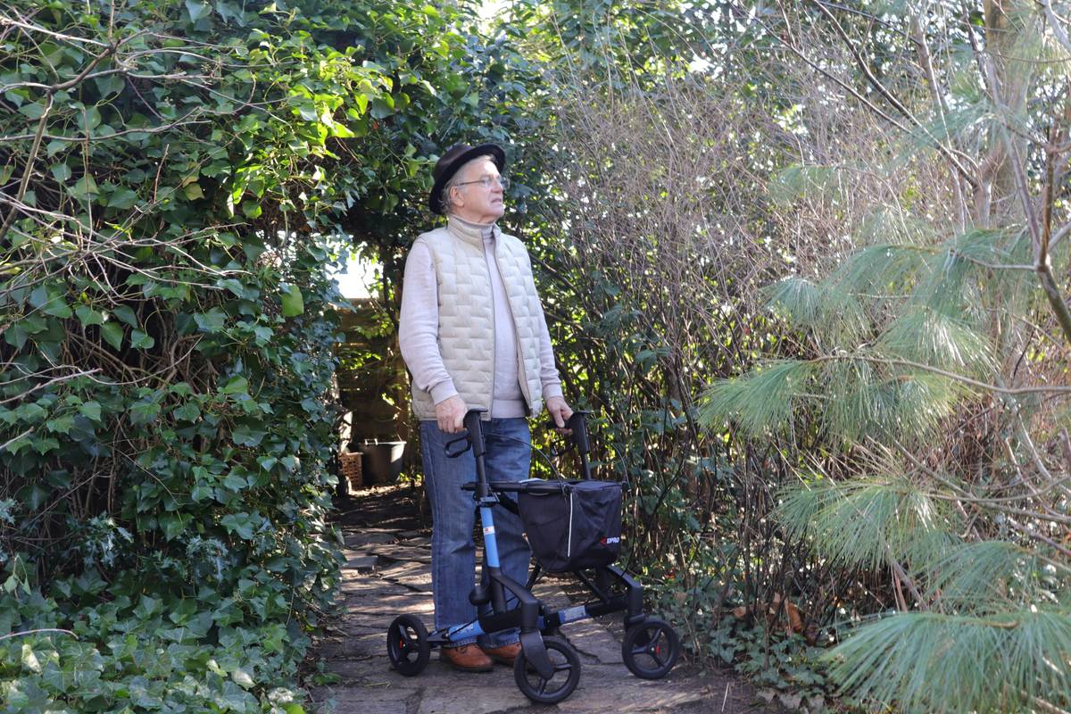 assisted living option community senior independent with smiling elderly couple walking in garden with caregiver nearby